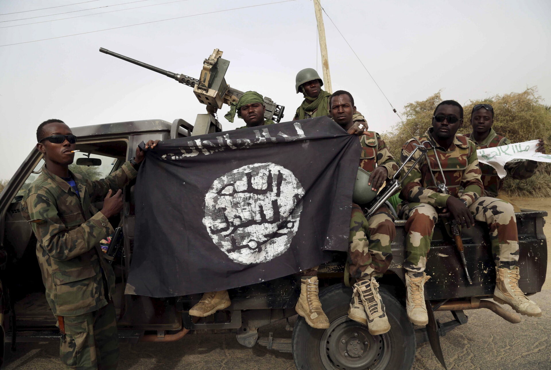 Nigerian soldiers hold up a Boko Haram flag that they had seized in the recently retaken town of Damasak, Nigeria