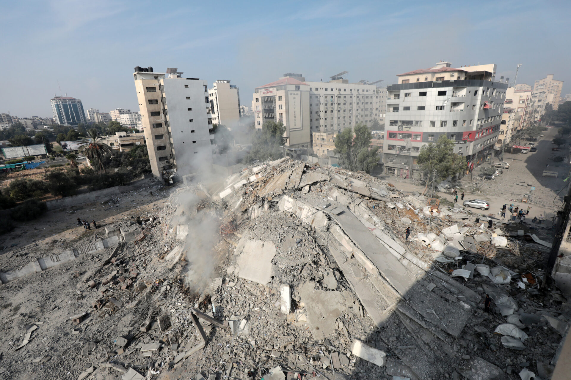 Palestinians inspect the ruins of Watan Tower destroyed in Israeli airstrikes